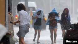 Para perempuan menerjang angin kencang akibat topan Neoguri di jalan Kokusai, Okinawa, Jepang (8/7). (Foto: Kyodo)