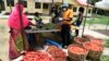 FILE - A vendor wearing a face mask, right, attends to a buyer at a Primary School converted to a makeshift food market for residents of the Ilupeju community in Lagos, Nigeria, April 3, 2020. 