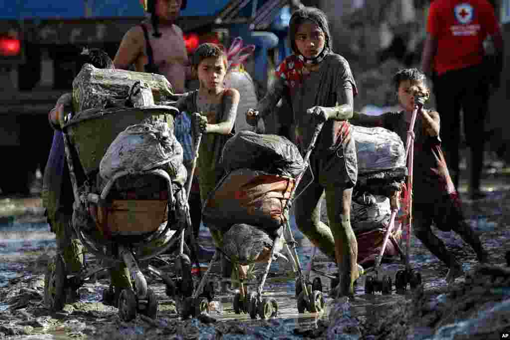 Children push baby strollers full of belongings they retrieved from their homes damaged by Typhoon Vamco in Rodriguez, Rizal province, Philippines.