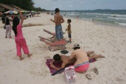 A Cambodian woman gives massage to a tourist on the beach of Sihanoukville, some 185 kilometers (115 miles) southwest of Phnom Penh, Cambodia July 29, 2006.
