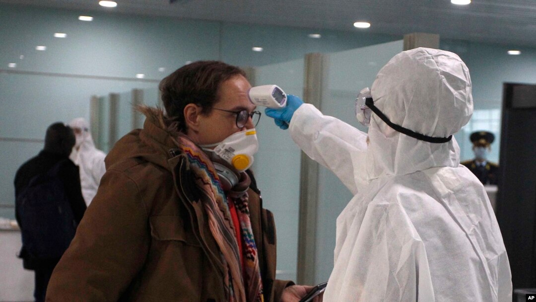 A passenger wearing a mask as a precaution against a new coronavirus has his temperature checked before boarding a flight to Vladivostok, Russia, at the Pyongyang International Airport in Pyongyang, North Korea, Monday, March 9, 2020. (AP Photo/Cha Song Ho)