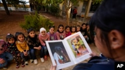 Displaced children, who fled Baalbek city and the nearby towns of Douris and Ain Bourday with their families amid the ongoing Hezbollah-Israel war, listen to a story at a school being used as a shelter, in Deir Al-Ahmar, east Lebanon, Oct. 31, 2024.