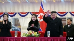 Pemimpin Korea Utara Kim Jong Un (kedua dari kanan) melambaikan tangan saat dia menonton pertunjukan besar Tahun Baru bersama putrinya (tengah), dan ibunya Ri Sol Ju (kiri) di Stadion May Day di Pyongyang. (Foto: KCNA via KNS/AFP)