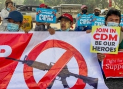 Anti-coup protesters hold up signs in support of Myanmar's Civil Disobedience Movement, during a rally in Yangon, Myanmar, Feb. 24, 2021.