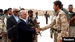 Iraqi Prime Minister Haidar al-Abadi, left, who was touring Anbar province, visiting army units, shakes hands with a Sunni tribesman at Camp Habbaniyah, in the eastern city of Ramadi, Iraq, April 8, 2015. 