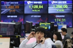 FILE - A currency trader talks on the phone at the foreign exchange dealing room of the KEB Hana Bank headquarters in Seoul, South Korea, March 25, 2020.