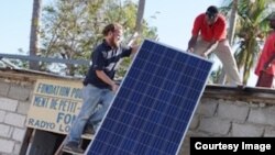 Christopher Alagna, Oficial de Tecnologías de la Información del PMA, ayuda a colocar paneles solares en una estación de radio en Nippes. Foto: WFP.