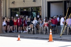 FILE - Students line up at a sports bar as Alabama prepares to play Texas A&amp;M, in Tuscaloosa, Ala., Oct. 3, 2020.