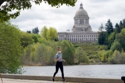 A person wears a mask while jogging, April 27, 2021, near the Capitol in Olympia, Washington.