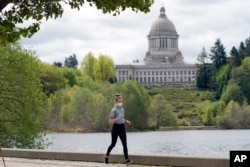 A person wears a mask while jogging, April 27, 2021, near the Capitol in Olympia, Washington.