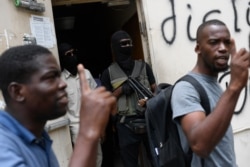 The bodyguards of current and former senators being questioned by prosecutors wait in the doorway outside the court, behind men who support the politicians in Port-au-Prince, Haiti, July 12, 2021.