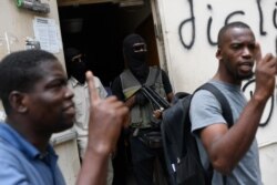 The bodyguards of current and former senators being questioned by prosecutors wait in the doorway outside the court, behind men who support the politicians in Port-au-Prince, Haiti, July 12, 2021.