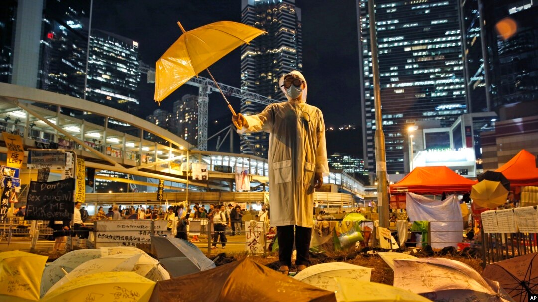 Seorang peserta aksi protes memegang payung kuning dalam sebuah pertunjukkan di jalan utama wilayah Admiralty, Hong Kong, 9 Oktober 2014 (Foto: dok). Ribuan warga diperkirakan akan turun ke jalan-jalan di Hong Kong, Jumat (30/6). 