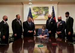 FILE - Republican Governor Brian Kemp signs S.B. 202, legislation that activists have said will curtail the influence of Black voters, in this handout photo posted to Kemp's Twitter feed on March 25, 2021.