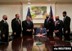 FILE - Republican Governor Brian Kemp signs S.B. 202, legislation that activists have said will curtail the influence of Black voters, in this handout photo posted to Kemp's Twitter feed on March 25, 2021.