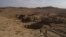 FILE - In this Nov. 11, 2017, photo, two Iraqi men walk near a sinkhole in Khasfa that is believed to contain the remains of people executed by Islamic State militants.