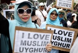 FILE - Women hold posters during a rally outside the Chinese Embassy in Jakarta, Indonesia, December 27, 2019. Over a thousand demonstrators called for an end to  oppression against Muslim Uighurs in China's region of Xinjiang.