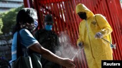 Un agent de la santé pulvérise du désinfectant sur une dame à Caracas, Venezuela, 18 mars 2020. (Photo: Reuters)