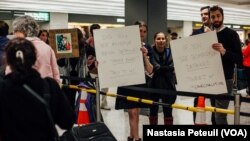 Des avocats accueillent les touristes et les résidents à l'aéroport international de Washington DC, le 31 janvier 2017. (VOA/Nastasia Peteuil)