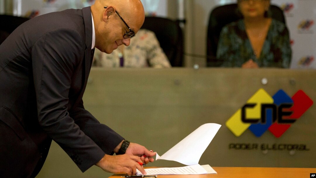El ministro de Comunicaciones, Jorge Rodríguez, firma en nombre del gobierno un acuerdo para postergar las elecciones.