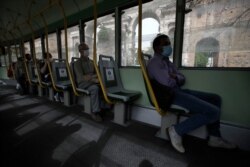 People wearing a sanitary mask and respecting social distancing to protect against COVID-19 sit on a tramcar, in Rome, Wednesday May 13, 2020. Italy partially lifted lockdown restrictions last week after a two-month lockdown. (AP Photo/Alessandra…