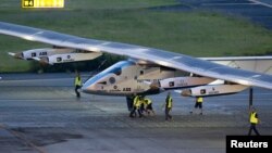 Crew members push the solar-powered plane Solar Impulse 2 to its parking position at Nagoya airport after changing weather conditions thwarted a planned take-off, June 24, 2015.