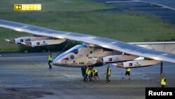 Crew members push the solar-powered plane Solar Impulse 2 to its parking position at Nagoya airport after changing weather conditions thwarted a planned takeoff, June 24, 2015.