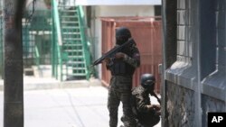 FILE - Police take cover during an anti-gang operation next to the National Palace in Port-au-Prince, Haiti, Monday, April 8, 2024.