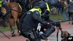 Dutch riot police kick a man during a demonstration to protest government policies including the curfew, lockdown and coronavirus related restrictions in The Hague, Netherlands.