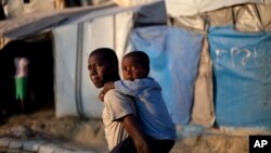 Seorang anak laki-laki menggendong adiknya ke sekolah, di sebuah tenda penampungan untuk korban gempa bumi 2010 di Port-au-Prince, Haiti (Foto: dok).