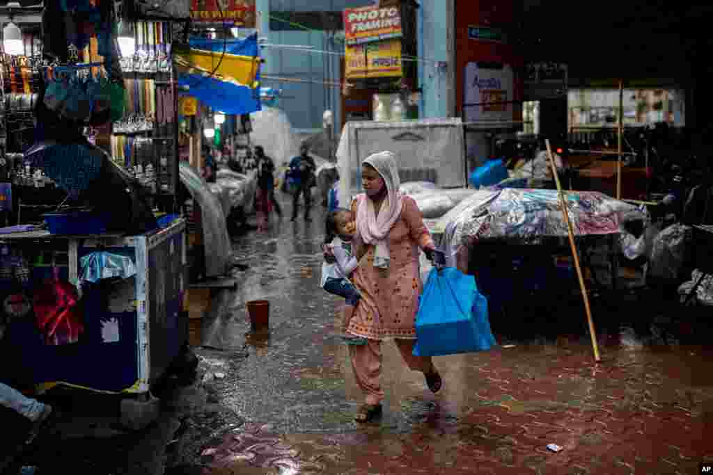 인도 뉴델리 외곽 노이다의 시장에서 한 여성이 장마철 소나기를 피하고 있다. 