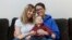 Anna Ford, left, and her partner, Sara Watson, pose with their son, Eli, in the village of Saunderstown, in Narragansett, R.I., Nov. 16, 2018.