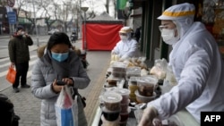 တရုတ်နိုင်ငံ Beijing မြို့မှာ ဗိုင်းရပ်စ် အန္တရာယ်ကာကွယ်ဖို့ ဝတ်စုံအပြည့်ဝတ်ပြီး ဈေးရောင်းနေတဲ့ ဝန်ထမ်းများ (သတင်းဓာတ်ပုံ - ဖေဖော်ဝါရီ ၂၀၊ ၂၀၂၀)