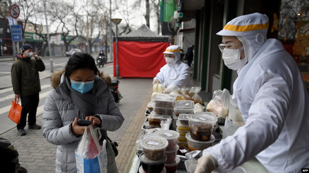 Karyawan restoran mengenakan pakaian pelindung saat berjualan di luar restoran mereka di Beijing, 20 Februari 2020.
