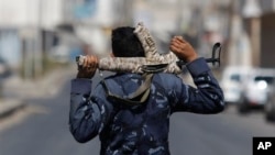 Policeman with cloth-covered weapon stands guard in Sanaa, Yemen, Feb. 23, 2014.