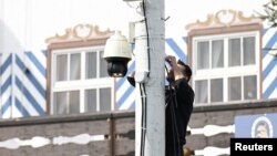 A worker installs a surveillance camera in front of a beer tent ahead of the 189th Oktoberfest, the world's largest beer festival, in Munich, Germany, Sept. 11, 2024.