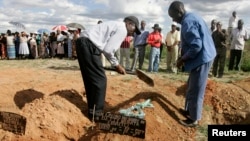 FILE: Relatives cover the grave of a cholera victim in Zimbabwe.