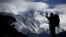 FILE - A tourist is silhouetted as he takes pictures of Mount Nuptse, center, as Mount Everest, left, is covered with clouds in Solukhumbu district, also known as the Everest region, Nov. 30, 2015.