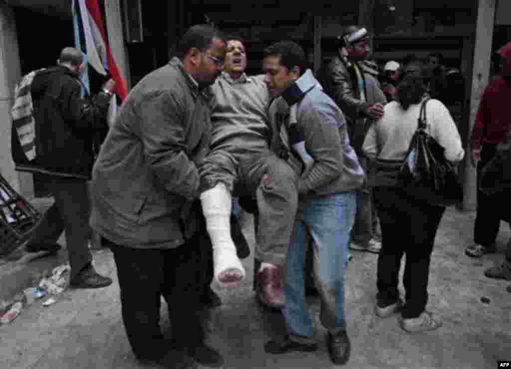 Anti-government demonstrators carry a man wounded during clashes with pro-government protesters, at a makeshift medical triage station, near Tahrir square, the center of anti-government demonstrations, in Cairo, Egypt, Wednesday, Feb. 2, 2011. Thousands o