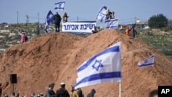 Pemukim Israel berkumpul dalam sebuah rally untuk mendukung pendirian kembali pos terdepan ilegal Eviatar dekat kota Nablus di Tepi Barat, Jumat, 18 Februari 2022. (Foto: AP)