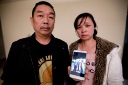 FILE - Ronggao Zhang, left, and Lifeng Ye, display a photo them with their missing daughter, Yingying Zhang, in Urbana, Ill., Nov. 1, 2017.