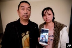 FILE - Ronggao Zhang, left, and Lifeng Ye, display a photo them with their missing daughter, Yingying Zhang, in Urbana, Ill., Nov. 1, 2017.
