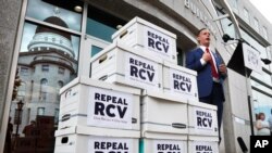 Jason Savage, executive director of the Maine GOP, speaks about efforts to repeal ranked choice voting while standing next to boxes containing signed petitions near the State House, June 15, 2020, in Augusta, Maine. 