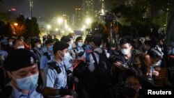 People look at police officers standing guard at Victoria Park on the 32nd anniversary of the crackdown on pro-democracy demonstrators at Beijing's Tiananmen Square in 1989, in Hong Kong, June 4, 2021. 