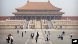 Para pengunjung mengenakan masker untuk melindungi diri dari virus corona, saat ber-selfie di Kota Terlarang, Beijing, China, 1 Mei 2020. 