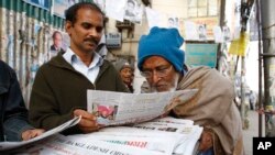 FILE - People catch up with news at a newspaper stall in Dhaka, Bangladesh.