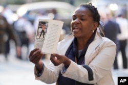 FILE - A woman yells and holds up a picture of Jordan Neely just before Daniel Penny arrives to Manhattan criminal court in New York, Oct. 21, 2024.