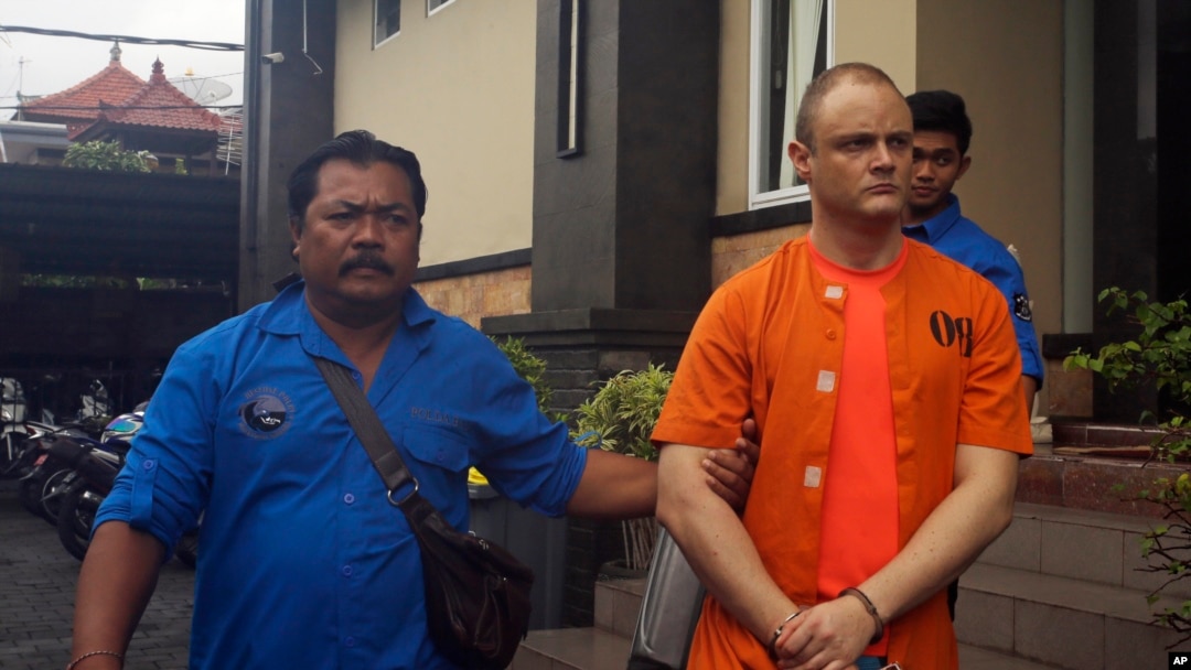 Petugas dari kepolisian Indonesia mengawal Isaac Emmanuel Roberts (warga Australia, berbaju oranye), setelah konferensi pers di Bali, 19 Desember 2017. (Foto: dok). Isaac dijatuhi hukuman 15 bulan rehabilitasi akibat terbukti melakukan kejahatan terkait narkoba di Bali.