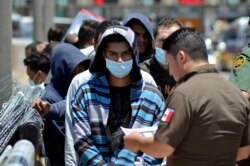 FILE - Mexican officials and U.S. Border Patrol officers return a group of migrants to the Mexico side of the border as Mexican immigration officials check the list, in Nuevo Laredo, Mexico, July 25, 2019.