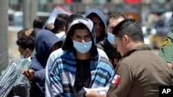 ARCHIVO - Funcionarios mexicanos y oficiales de la Patrulla Fronteriza de EE.UU. devuelven a un grupo de migrantes al lado mexicano de la frontera mientras los funcionarios de inmigración mexicanos revisan la lista, en Nuevo Laredo, México, el 25 de julio de 2019.
